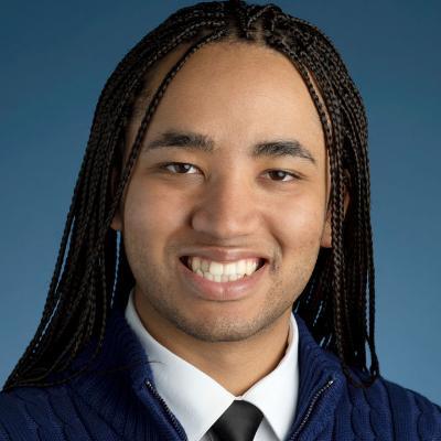 Daniel Burnett smiling in headshot tie and blue background